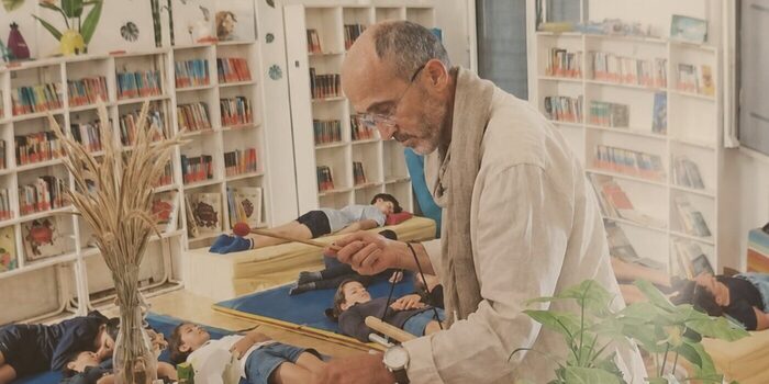 Didier leads a relaxation session in a library, with children lying on mats