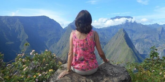 A woman sitting on a rock, looking out over the mountains of Réunion Island