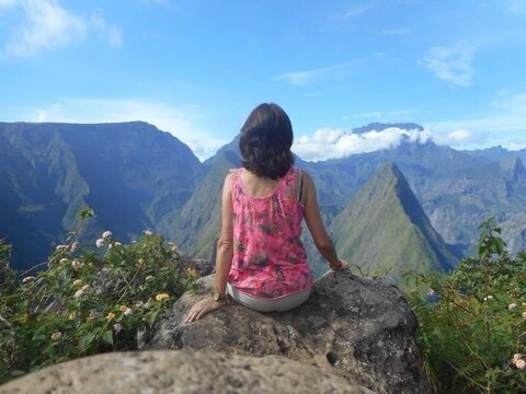 A woman sitting on a rock, looking out over the mountains of Réunion Island